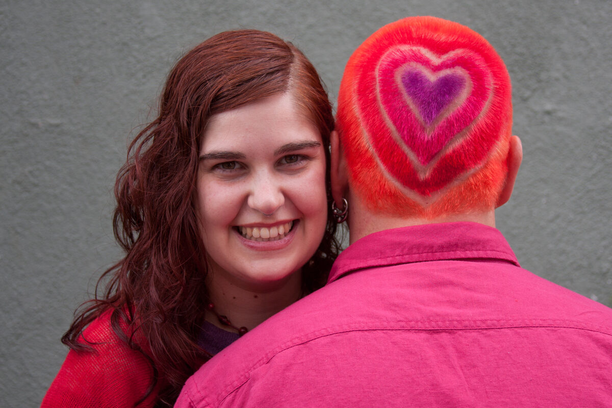 Concentric hearts in red, pink, and purple dyed into the back of Rob's head, visible where the hair curves toward the neck.
