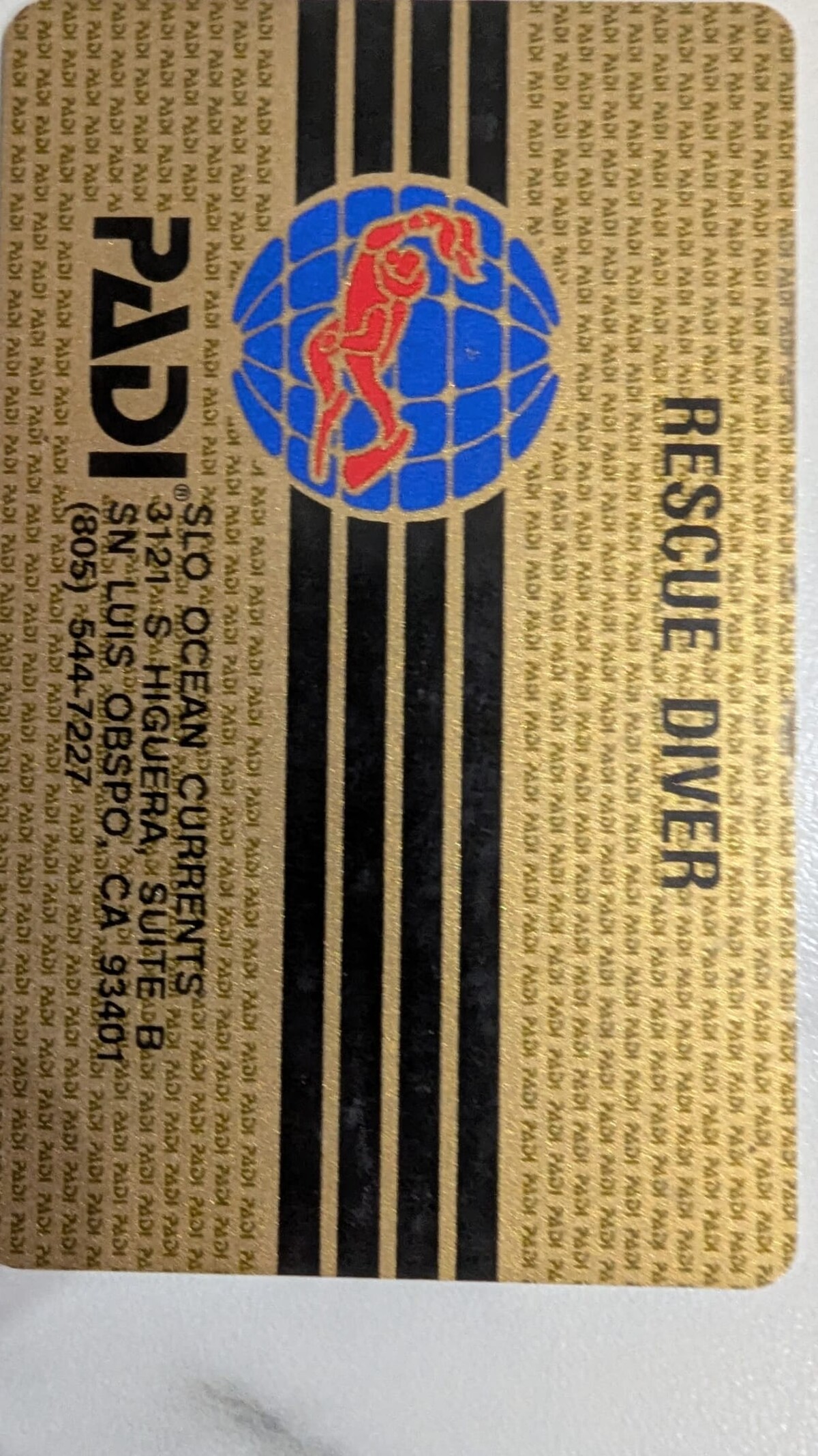 Gold PADI Rescue Diver certification card, front side. Printed text reads Rescue Diver with the dive shop name SLO Ocean Currents, address on South Higuera Street, San Luis Obispo, and phone number.