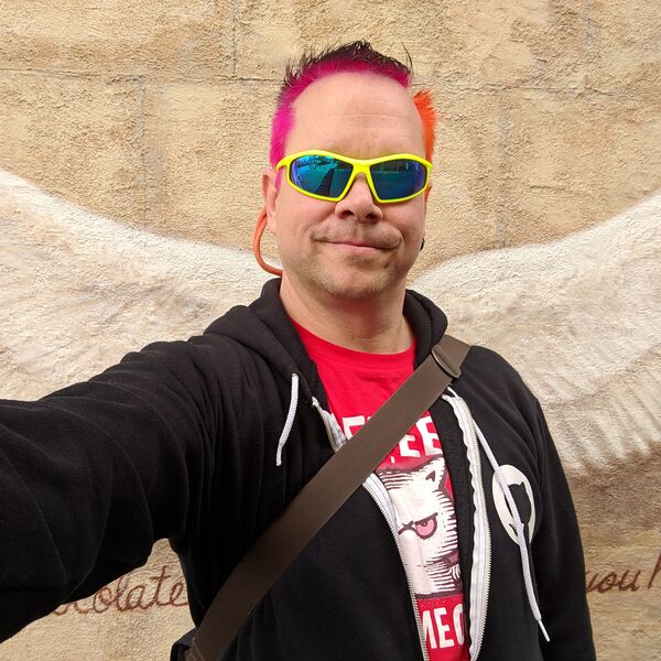 Rob selfie with angel wings mural in Japan, pink hair, neon yellow sunglasses
