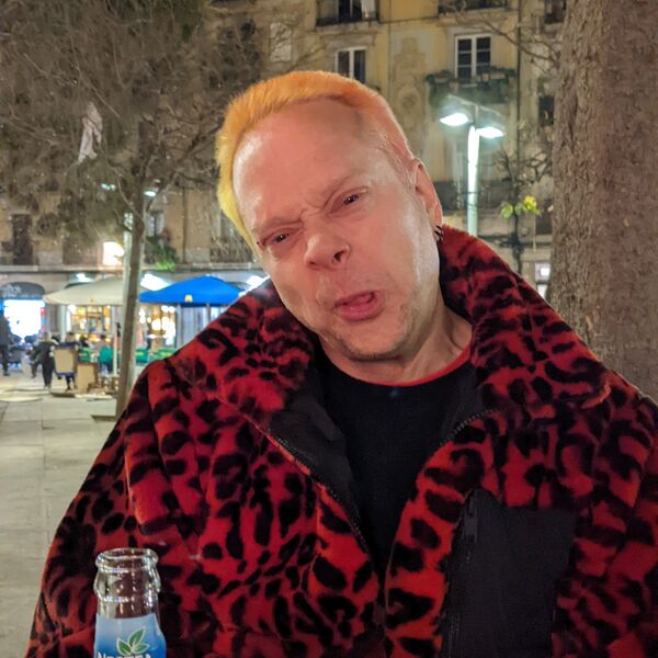 Rob in a red leopard-print jacket at night in Barcelona, orange hair