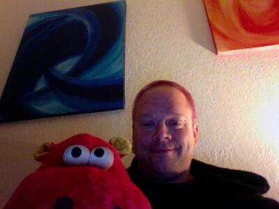 Rob lying with Rumpskins, his beloved large red stuffed dinosaur, at home